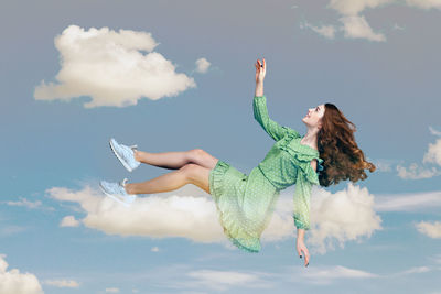 Low angle view of woman with arms raised against sky