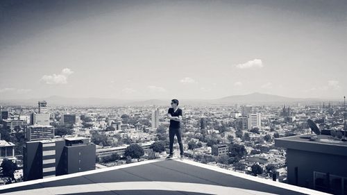 Man standing by cityscape against sky