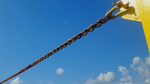 Low angle view of chain against blue sky