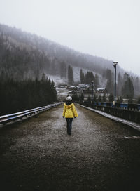 Rear view of woman walking on road during foggy weather