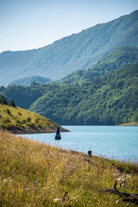 Scenic view of lake by mountains against sky