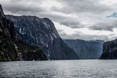 Scenic view of sea by mountains against sky