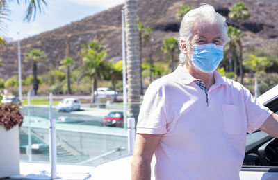 Portrait of senior man wearing mask standing outdoors