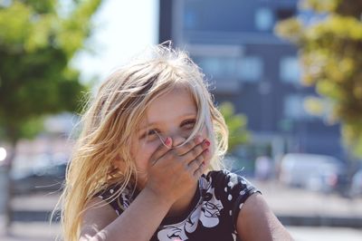 Portrait of cute girl with hand covering mouth