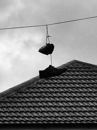 Low angle view of bird perching on roof against sky