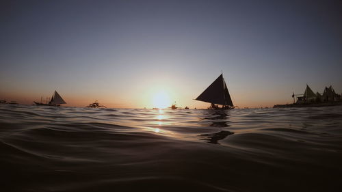 Boats in sea against sky during sunset