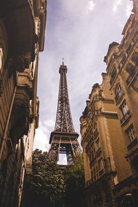 Low angle view of eiffel tower by buildings against sky