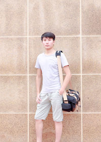 Portrait of boy standing against wall