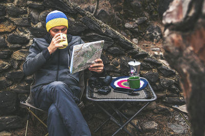 Man photographing while sitting on rock