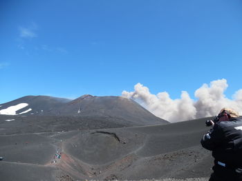 Man photographing etna volcano eruption with camera