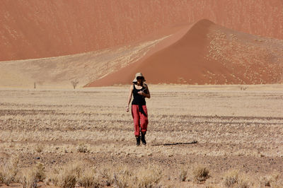 Full length of woman standing on field in desert 