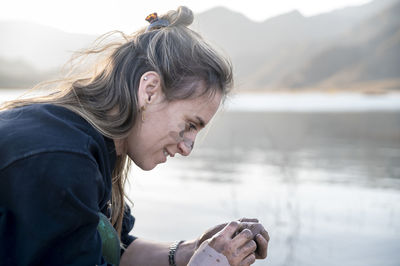 Woman putting mud on hands and face while enjoying outdoors in nature.