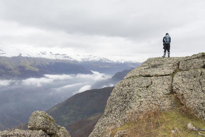 Rear view of man standing on mountain against sky