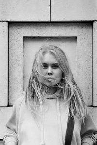 Portrait of young woman against wall