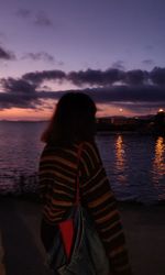Woman on beach against sky during sunset