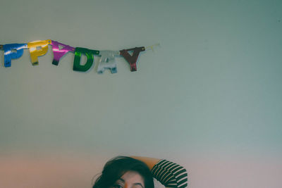 Portrait of woman standing against birthday decoration on wall