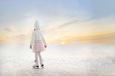 Little girl skating on ice in evening sunset light. winter sports on natural background.