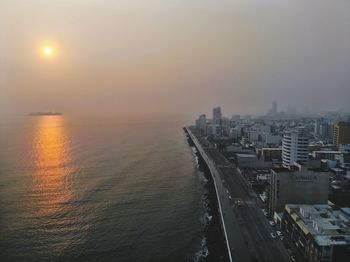 High angle view of buildings by sea against sky during sunset