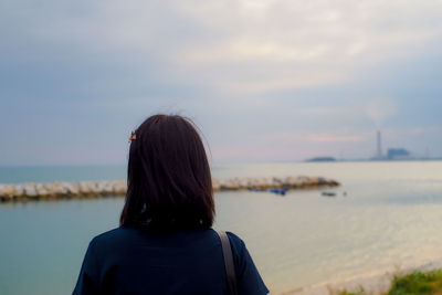 Rear view of woman on beach against sky