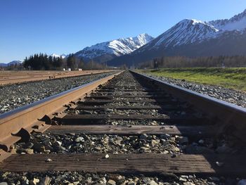 Railroad track by mountains against clear sky