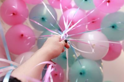 Close-up of hand holding pink balloons