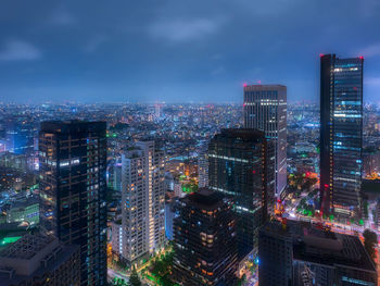 Illuminated buildings in city against sky at night