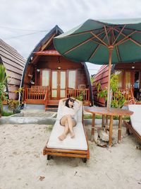 Rear view of woman sitting on lounge chair at beach