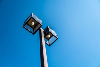 Low angle view of illuminated street light against blue sky