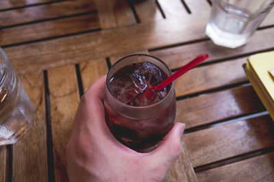 High angle view of hand holding glass on table