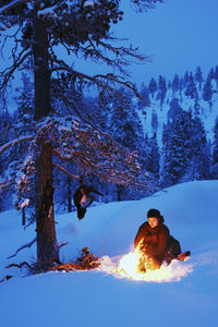 Man with snow covered land and trees against sky