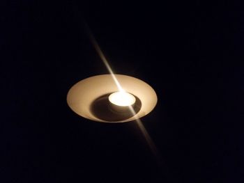 Low angle view of illuminated light bulb against black background