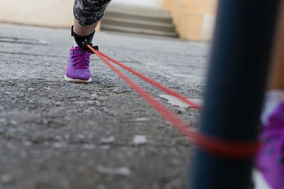 Low section of woman wearing while resistance band on road