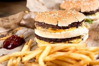 Close-up of hamburger and french fries with ketchup on paper