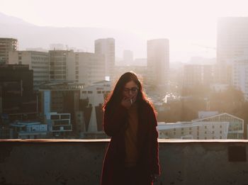 Young woman standing against buildings in city during winter