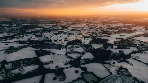 High angle view of snowcapped landscape against sky during sunset