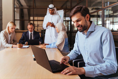 Business colleagues using laptop while sitting on table