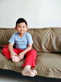 Portrait of smiling boy sitting on sofa at home