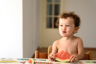 Portrait of cute girl eating fruit sitting at home