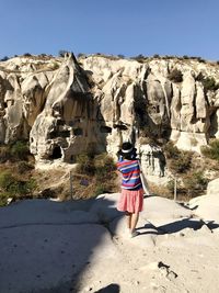 Rear view of woman on rock against sky