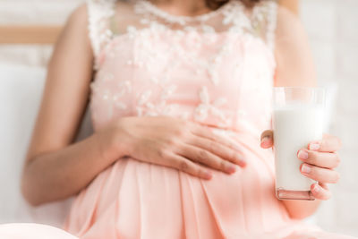 Midsection of pregnant woman holding milk glass