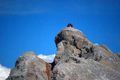 Low angle view of people on cliff against clear sky