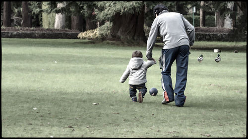 Rear view of father and son walking on golf course