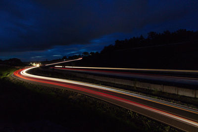 Light trails on road against sky at night