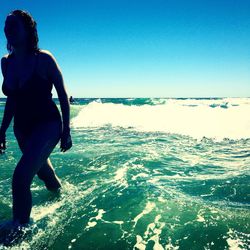 Rear view of woman standing by sea