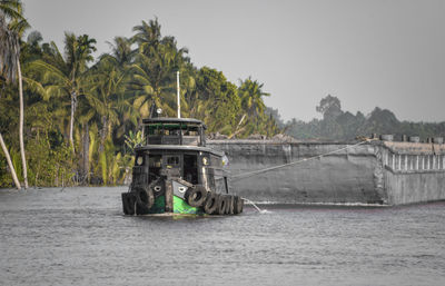Small tug boat pulls big barge at mekong delta