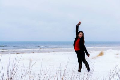 Portrait of woman standing at beach against sky during winter