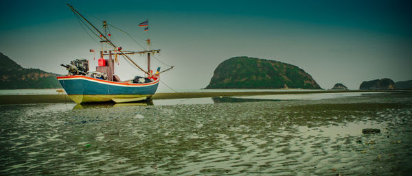 Sailboats moored on sea against sky