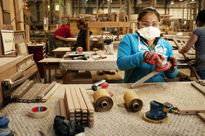 Carpenters sanding wooden plank at workshop