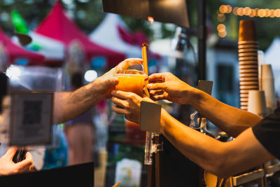 Male bartender serving healtyh drink to customer in plastic takeaway glass.