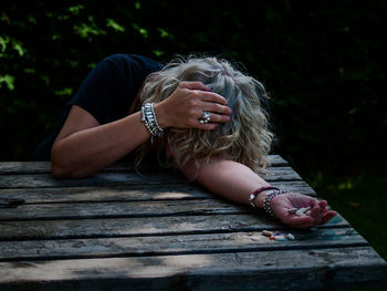 Woman holding medicine while sitting on table outdoors